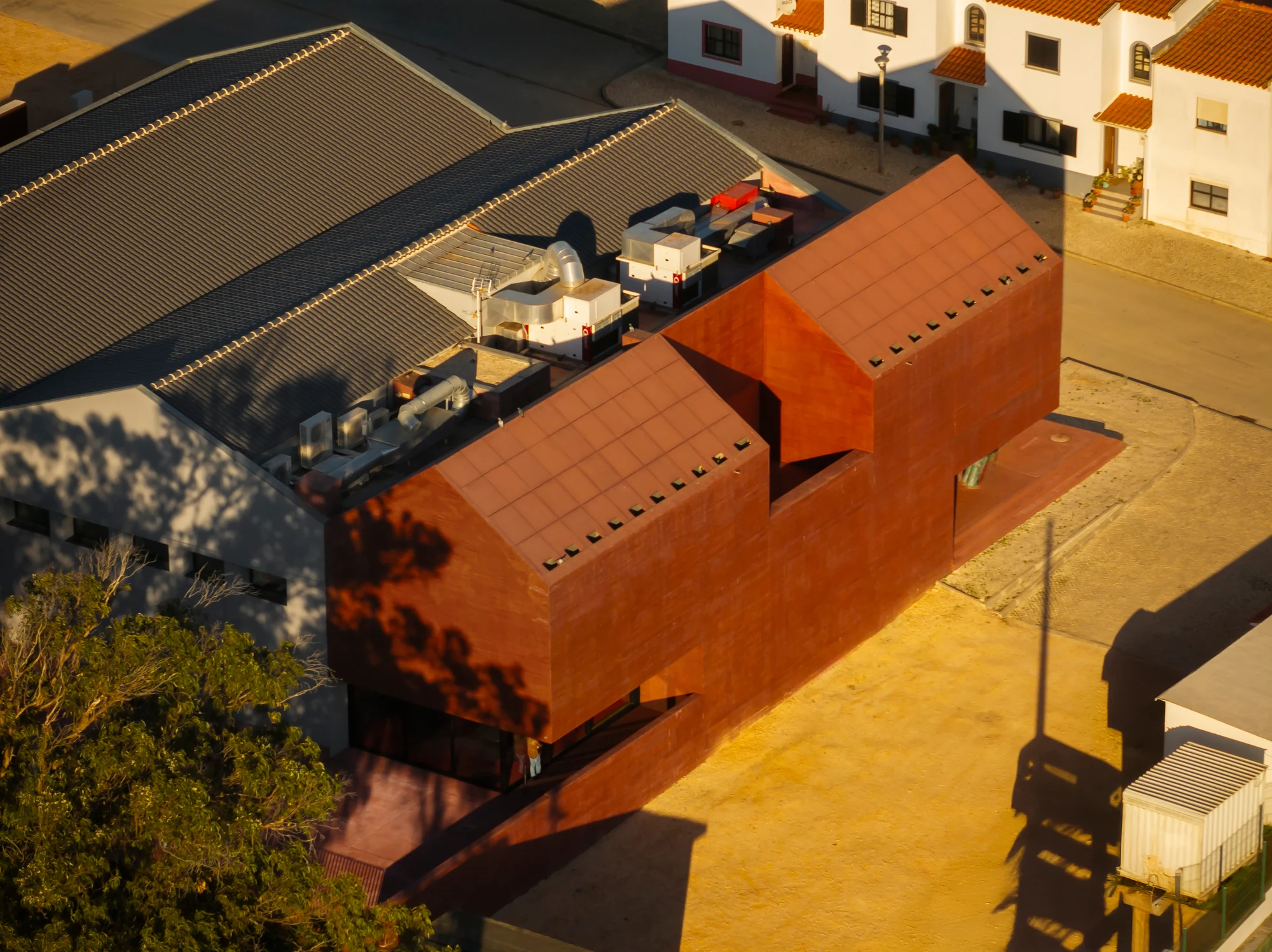 Vista aérea do Museu de Vila do Bispo, com o novo volume em betão pigmentado vermelho ligado às antigas naves